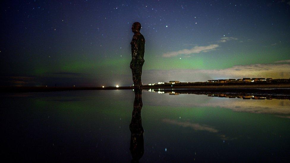 Northern Lights above one of the iron men statues at Anthony Gormley's Another Place, on Crosby Beach, Merseyside