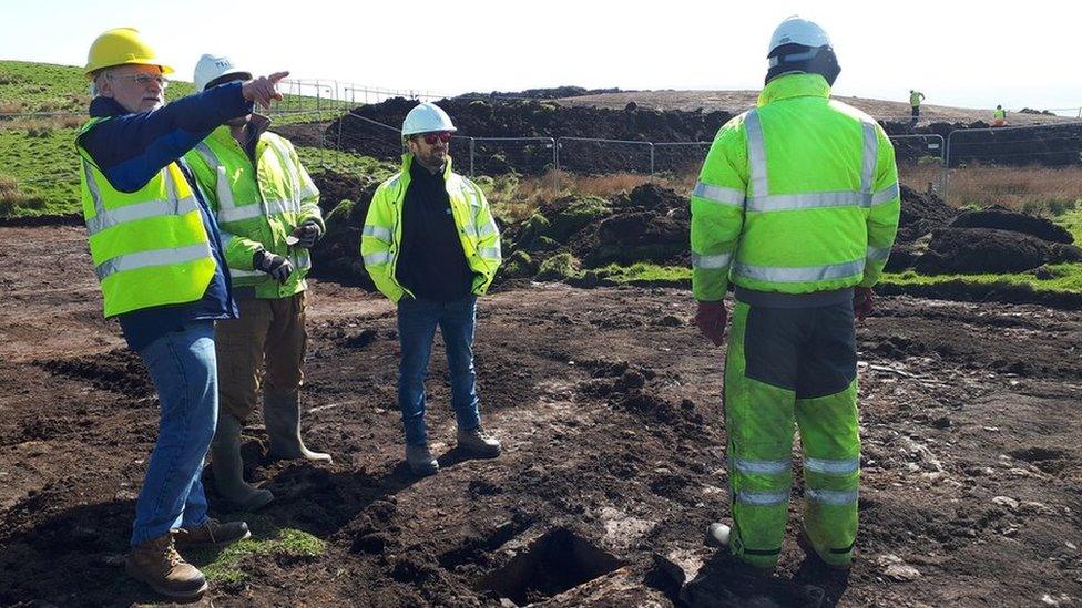 Archaeologists standing round cist