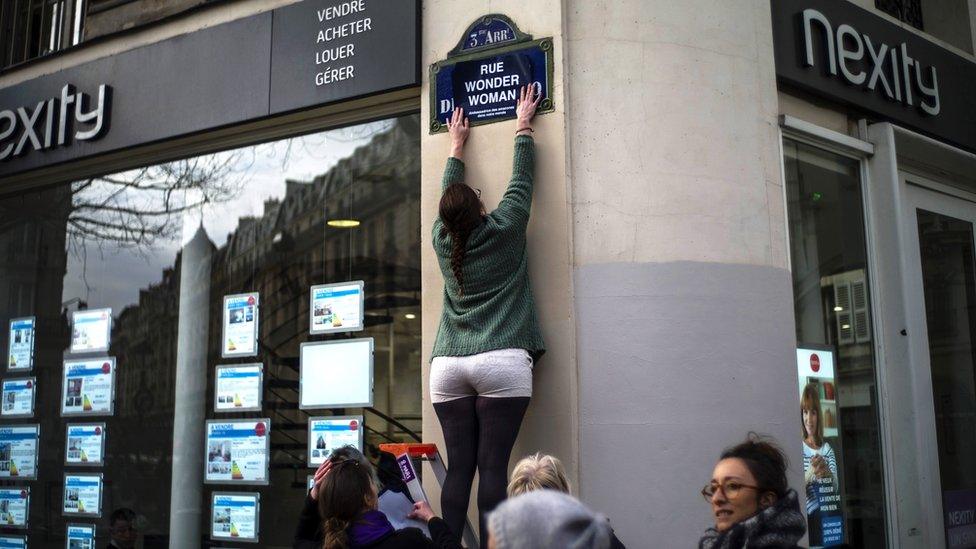 An activist renames a street with a sticker reading "Wonder Woman Street" during a so-called "Feminist Strike" demonstration on International Women's Day in Paris, France,