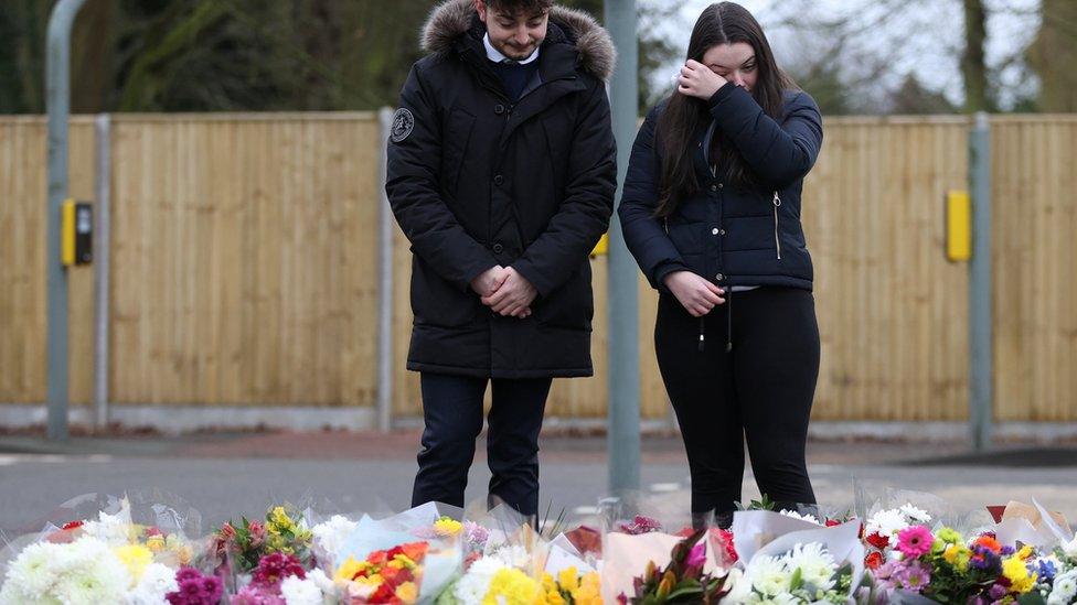 People look at flowers left near to the residence of Captain Sir Tom Moore, after his family announced that the centenarian fundraiser had died