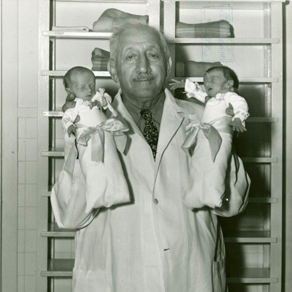 Martin Couney holding two babies