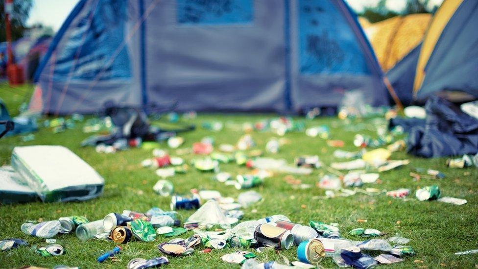 A shot of a festival campsite strewn with litter.