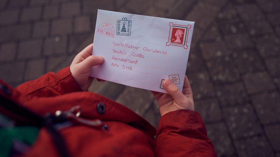 Child hands hold a letter addressed to Father Christmas