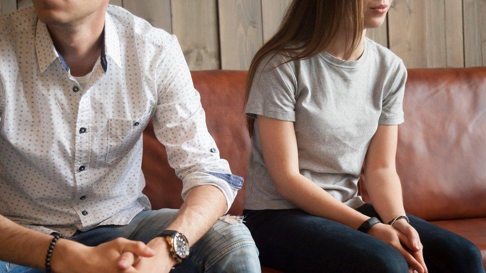 A couple sitting down with their arms crossed