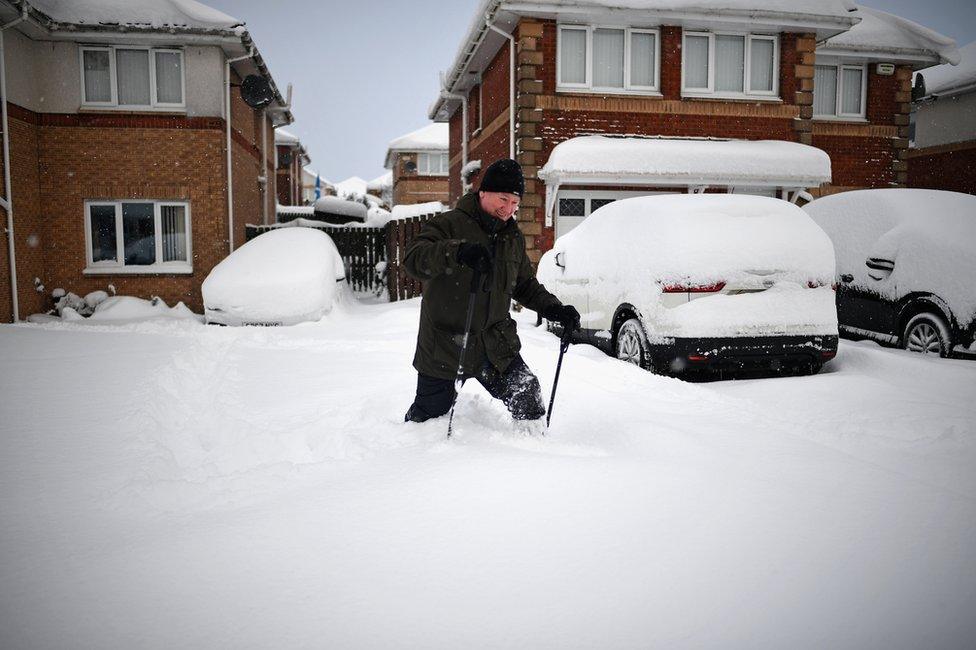 A man makes his way through snow in a housing estate