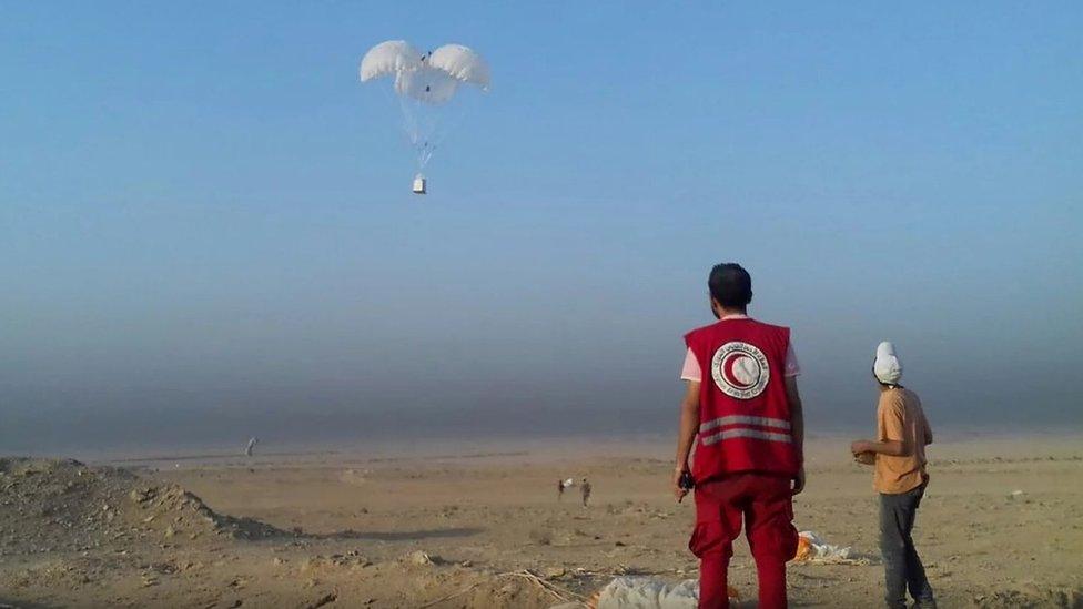 A worker from WFP's partner, the Syrian Arab Red Crescent, prepares to collect air-dropped cargo outside Deir al-Zour