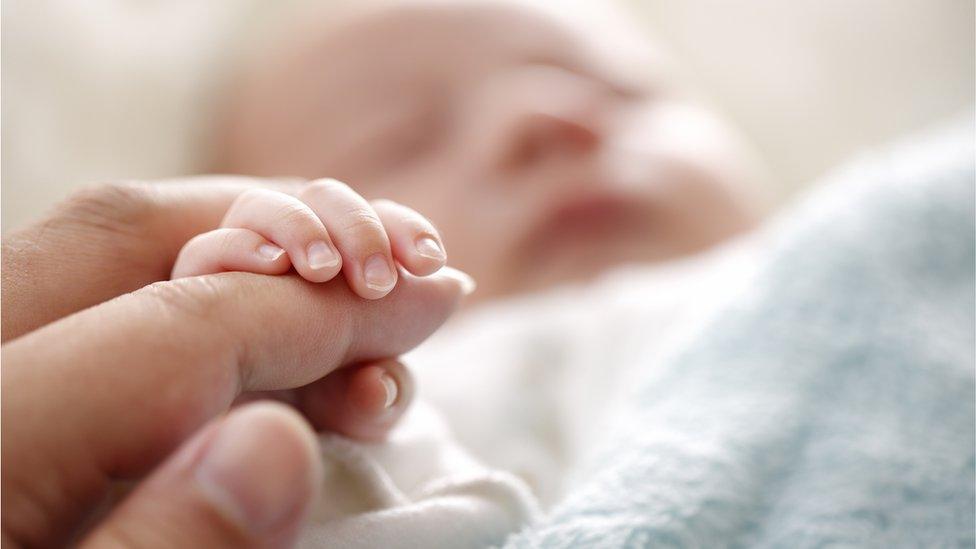 baby and mother hold hands