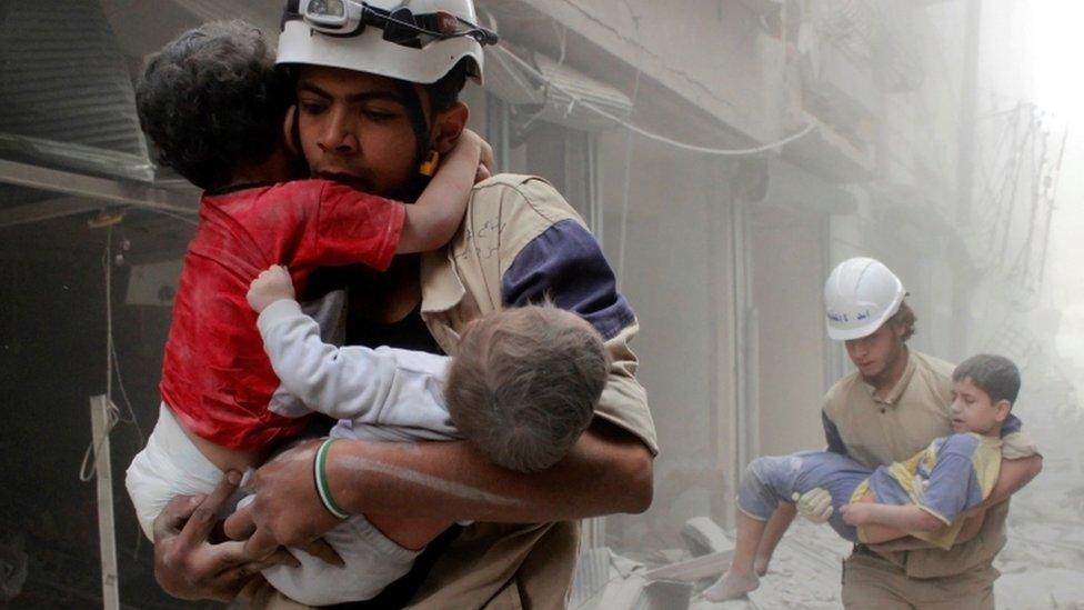 Rescue workers carry children to safety after an airstrike in Syria in Aleppo in 2014