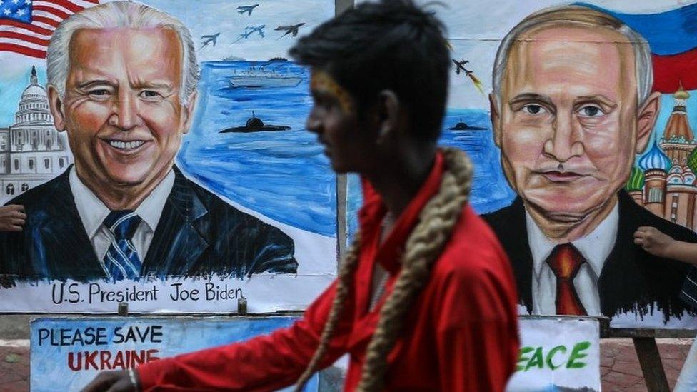 A man walks past students of the Gurukul School of Art painting portraits of US President Joe Biden and Russian President Vladimir Putin with a message wishing peace between Ukraine and Russia, in Mumbai, India, 21 February 2022.