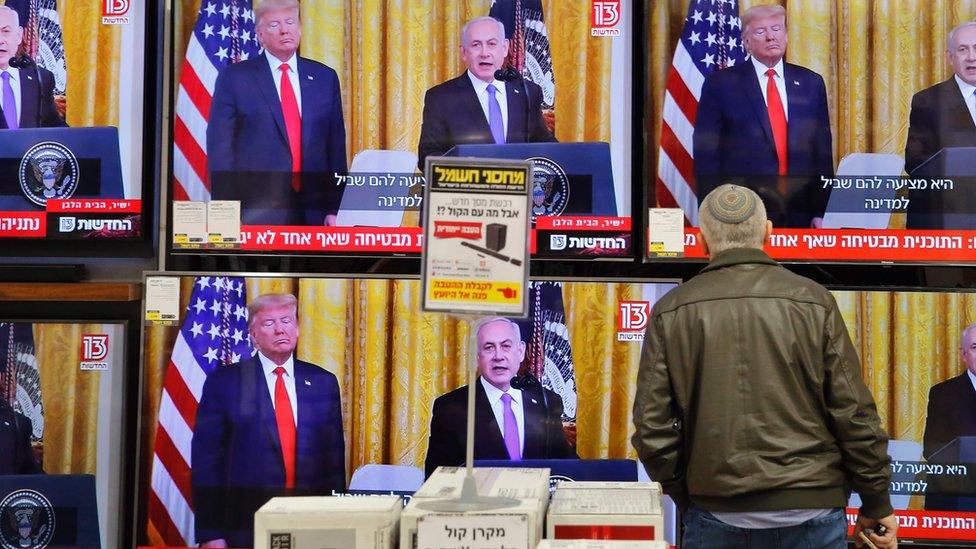 An Israeli man watches the televised press conference of US President Donald Trump and Israeli Prime Minister Benjamin Netanyahu at an electronics shop in the Israeli city of Modiin