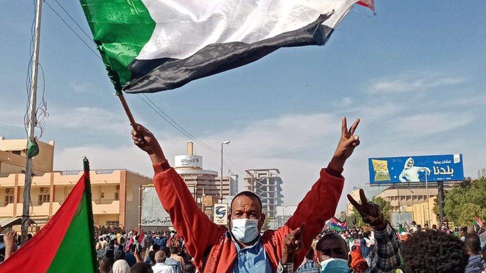 A Sudanese protester waves the national flag during a rally to mark three years since the start of mass demonstrations that led to the ouster of strongman Omar al-Bashir, in the capital Khartoum on December 19, 2021.