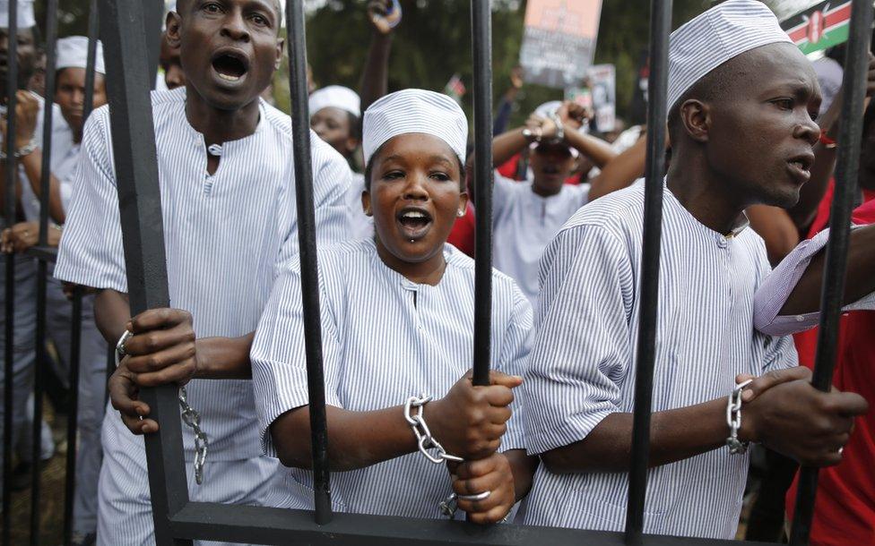 Protesters wearing mock prison uniforms walk with a mock prison pen to demand corrupt government officials to be jailed during a demonstration to demand President Uhuru Kenyatta to act on corruption or resign, in downtown Nairobi, Kenya, 03 November 2016