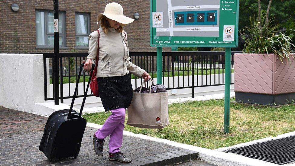 A resident with belongings leaves Taplow Tower residential block on the Chalcots Estate in north London