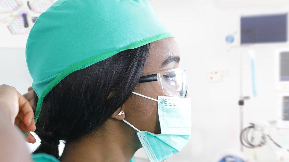 Woman wearing green scrubs and PPE