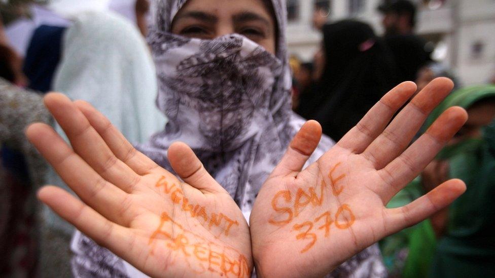 A Kashmiri woman shows her hands with messages at a protest after Friday prayers during restrictions in Srinagar on 16 August 2019