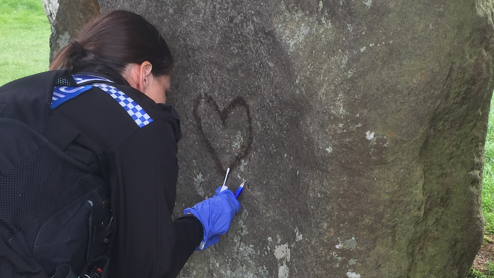 Photo of a police officer taking a sample from the graffiti