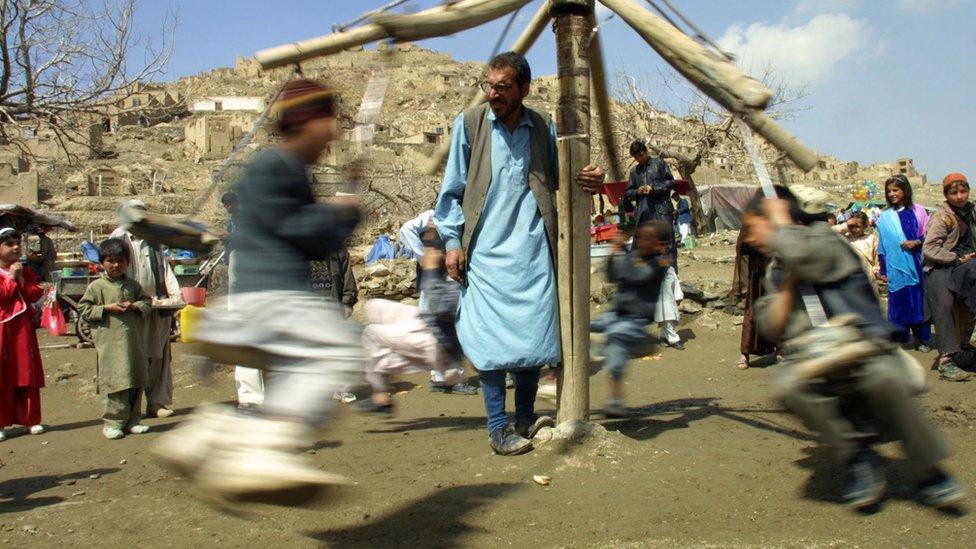 Afghan children enjoying a ride during the first Nowruz festival after the fall of the Taliban who banned the celebrations