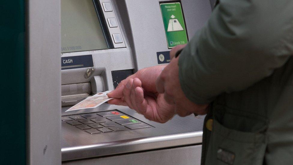 Man withdraws note from cash machine