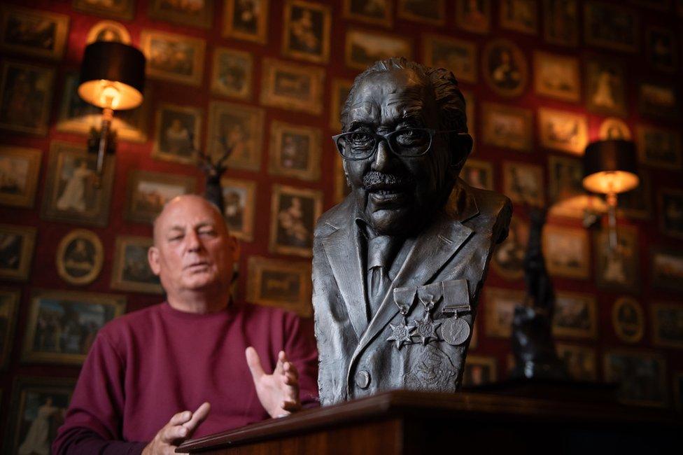 The bronze bust of Captain Sir Tom Moore with a man standing behind it