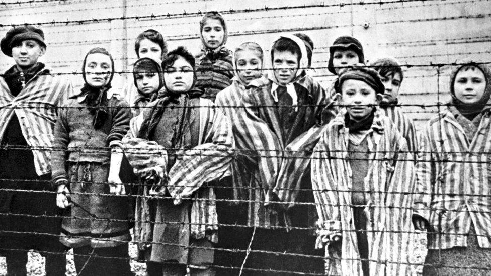 A group of child survivors behind a barbed wire fence at the Nazi concentration camp at Auschwitz-Birkenau in southern Poland, 27 January 1945