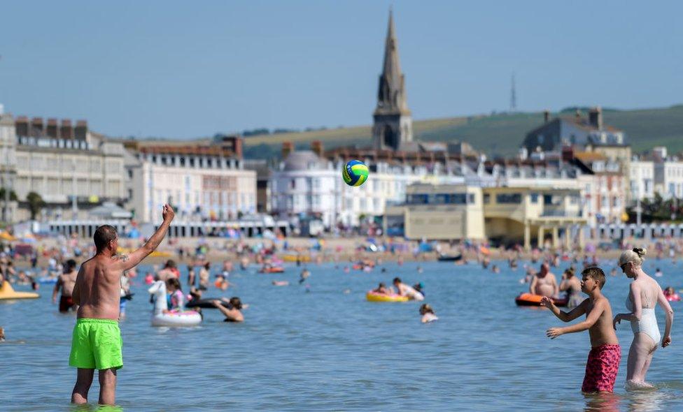 A man and boy play in the sea on July 18, 2021 in Weymouth, England