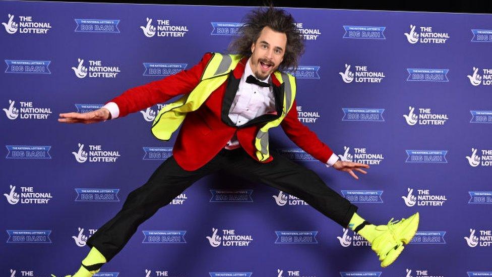 Viggo Venn, a comedian wearing a high-vis jacket, jumps in the air