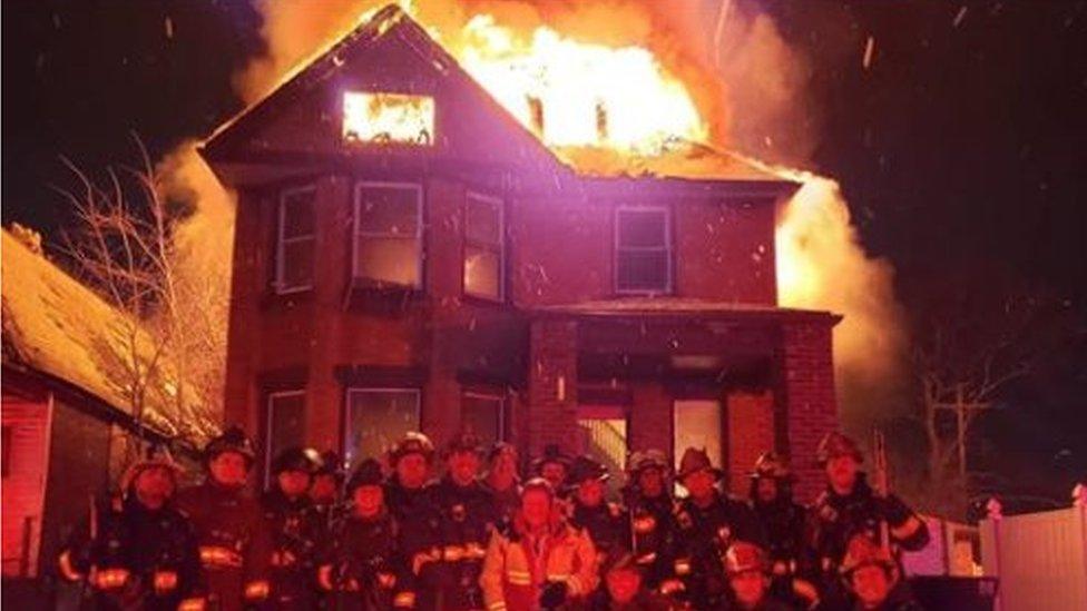 Fire crews posing for photo outside burning building