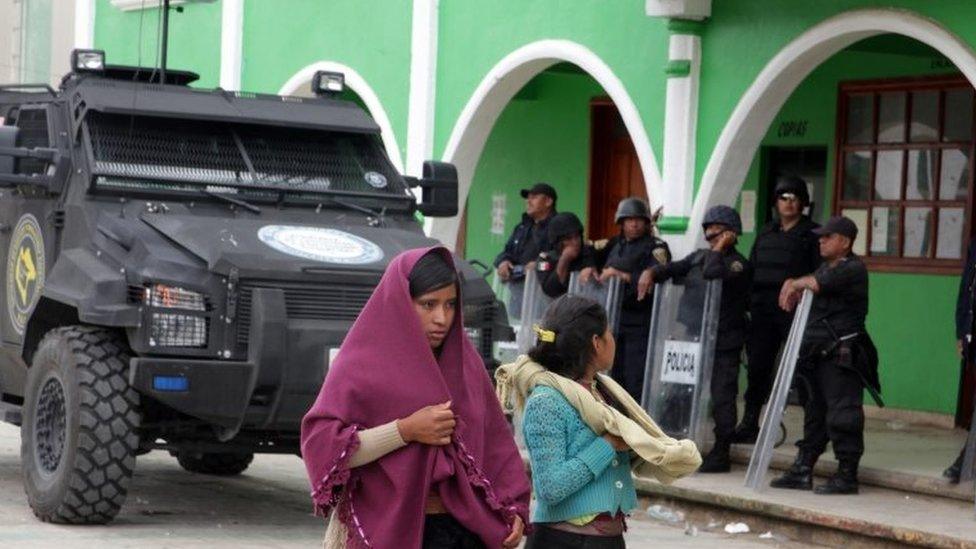 Indigenous women pass police officers standing guard in San Juan Chamula, Chiapas, Mexico, 23 July 2016