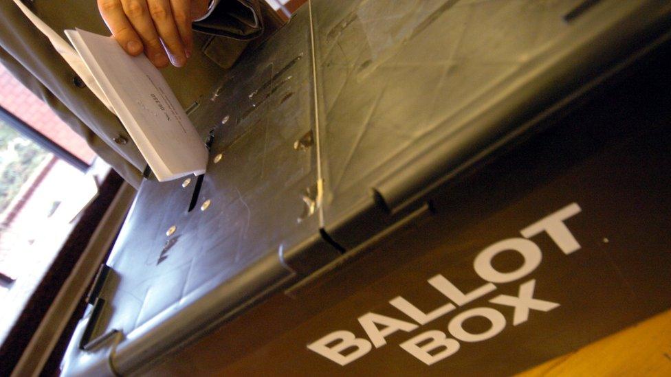 Voter placing paper in a ballot box