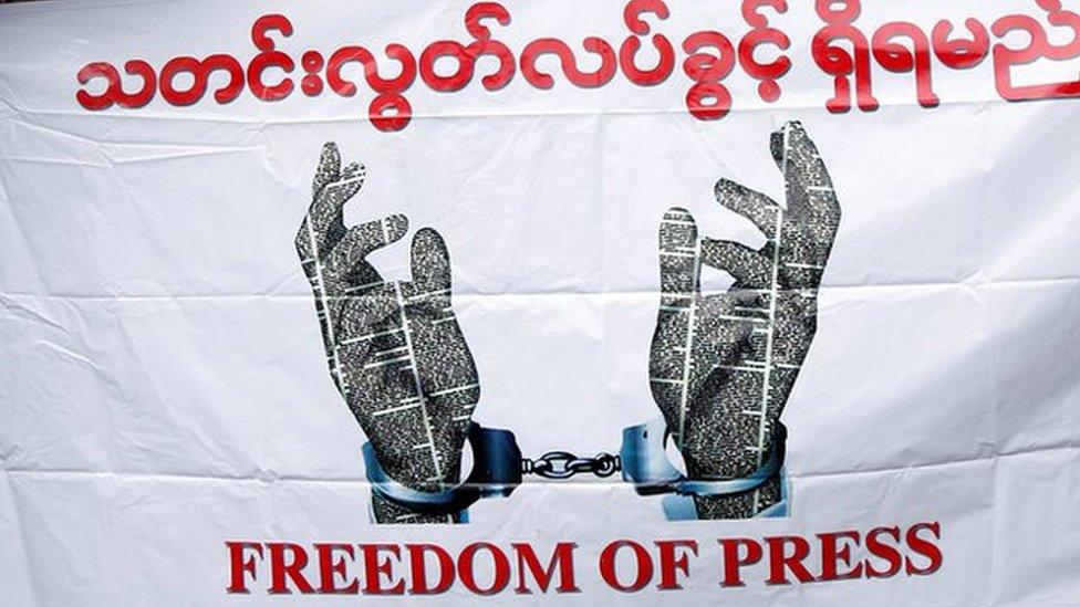 Journalists hold a banner as they protest against a law they say curbs free speech, at the start of a trial of two journalists who the army is suing for defamation over a satirical article, in Yangon