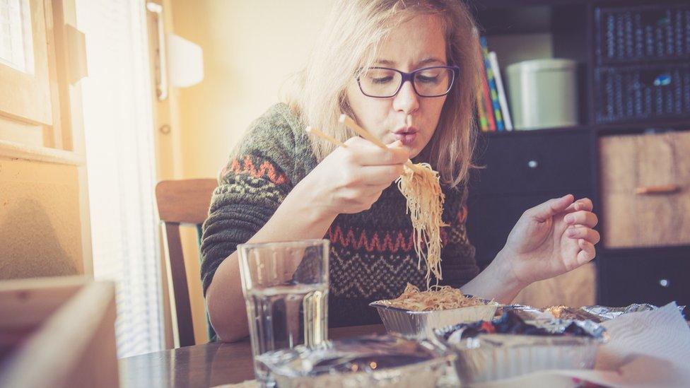 Woman eating takeaway noodles