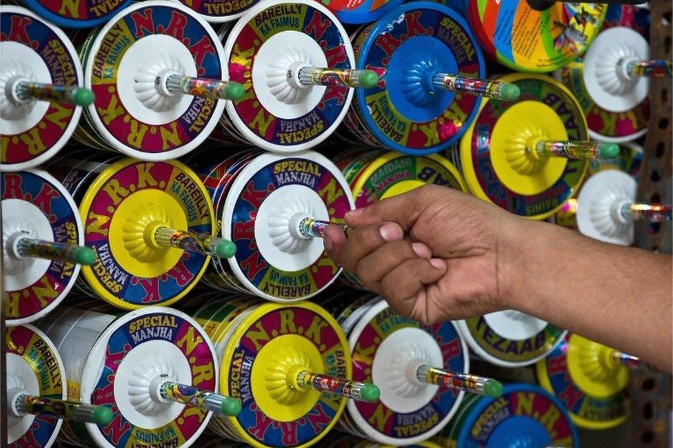 This file photograph taken on August 6, 2014 shows an Indian kite-maker removing a reel of kite string to be used at his shop ahead of Independence Day celebrations in New Delhi on August 6, 2014