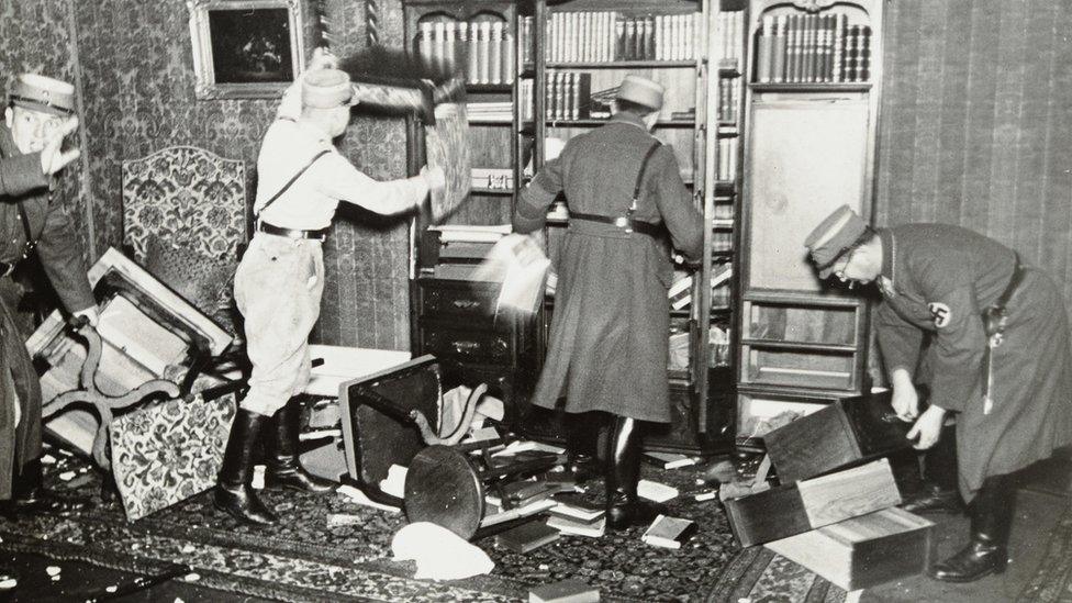 Officers tearing down books from a bookshelf