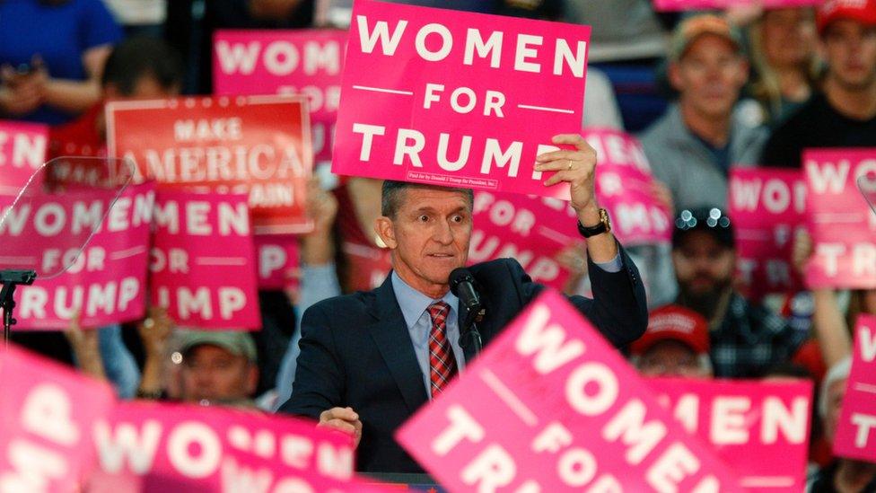 General Flynn hold a pink Women for Trump sign against his head during an election rally