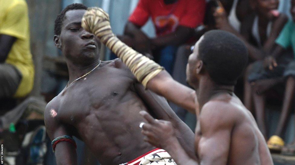 Dambe boxers fight with one hand neatly wrapped with cloth and knotted with a cord during a dambe match at Kara-Isheri in Ogun State, southwest Nigeria on July 24, 2016. Dambe is a traditional boxing associated with Hausa people in Nigeria and West Africa sub-Region. In Dambe, there are no formal weight categories, competitors are matched mostly based on age and size. Though the fight rarely exceed three rounds, a fighter is declared winner when an opponent's hand, knee, body touches the ground, or is Knocked down. Unlike the Western traditional boxing style which allow boxers to wear gloves to cover fists, Dambe boxers simply wraps their strong-side fist with a piece of cloth and covered by tightly knotted cord.