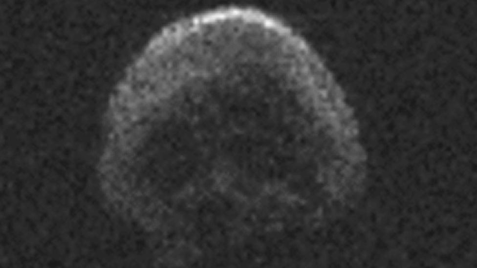 A grainy image of an asteroid, shaped like a human skull