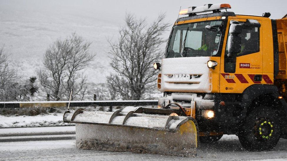 A salt gritter truck clears snow from the road during heavy snowfall in Glenshane Pass, Northern Ireland