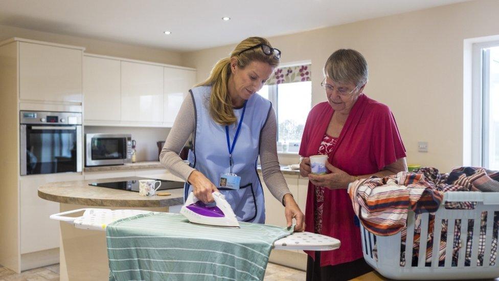 A carer helps an elderly woman