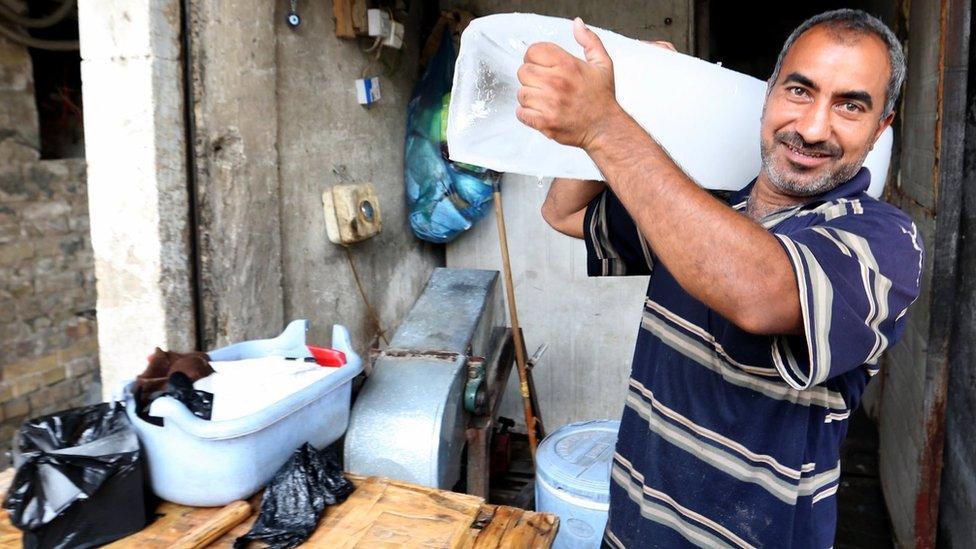 Iraqi man cuts a block of ice to sell it in Baghdad, Iraq, 6 July 2017