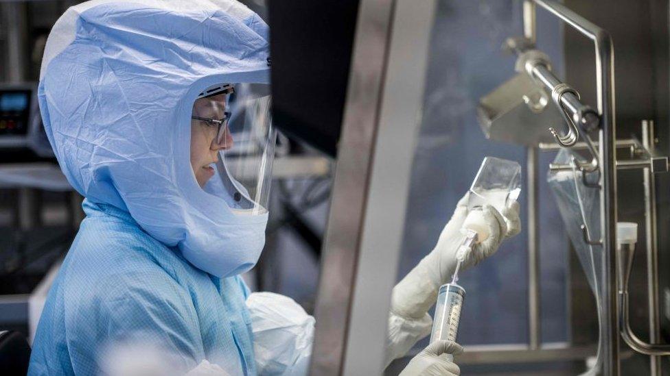 Employee in cleanroom suit at a laboratory workstation