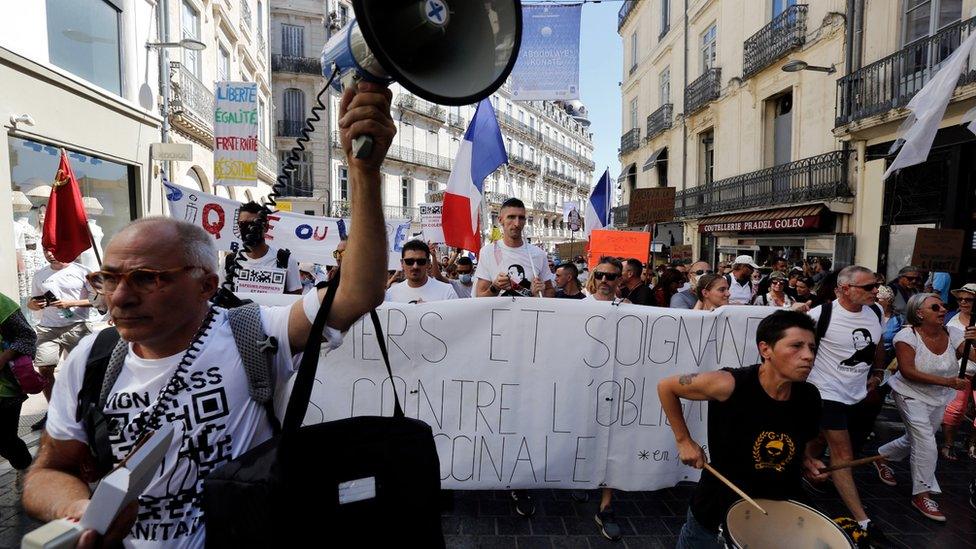 Protesters holds a banner reading "Firefighters and health workers against the vaccine obligation" during a demonstration against the COVID-19 sanitary pass