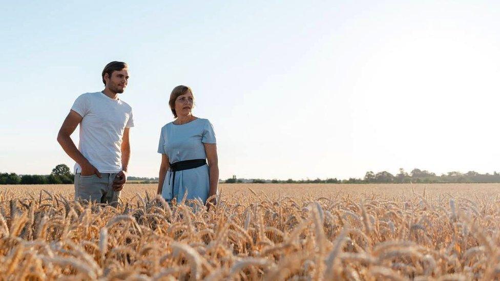 Nadiya and her son Dmytro standing in one of their wheat fields.