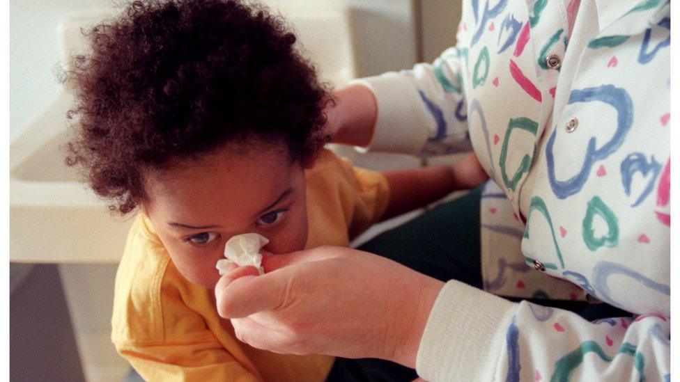 A woman wipes a child's nose