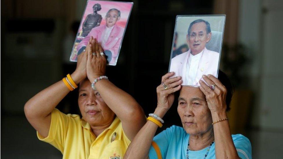 Thai women hold pictures of the king outside the hospital in Bangkok (10 Oct 2016)