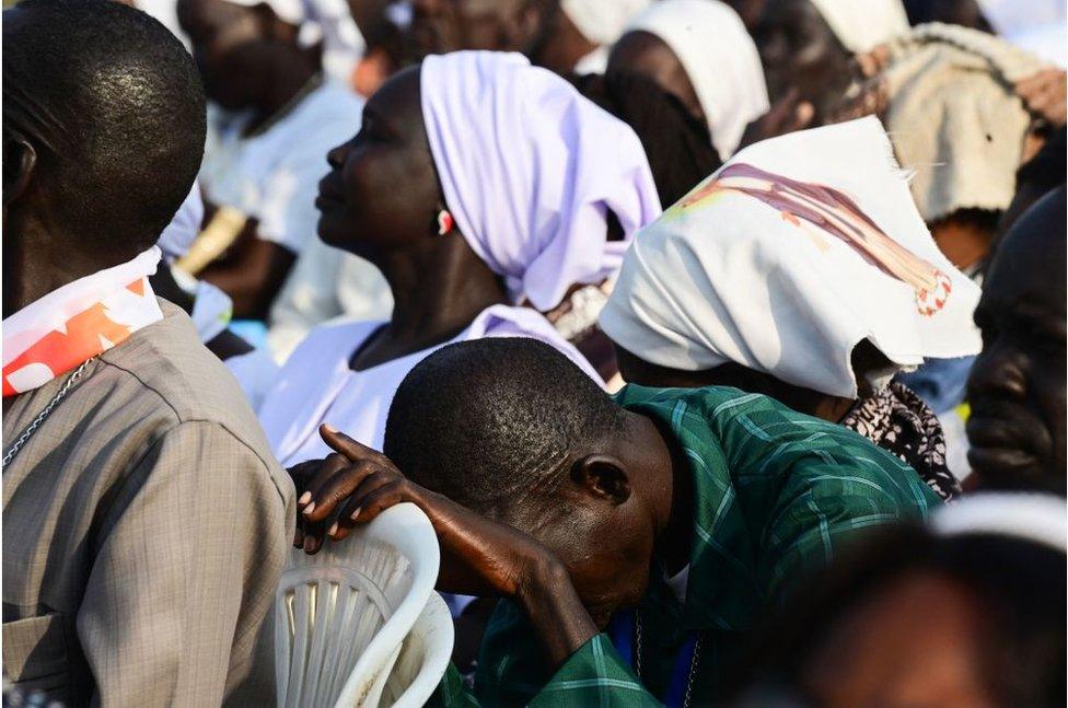 Man who appears to be praying in a crowd of people