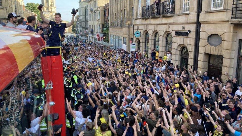 Hundreds of fans seen cheering in the High Street as Oxford United team arrive on the bus