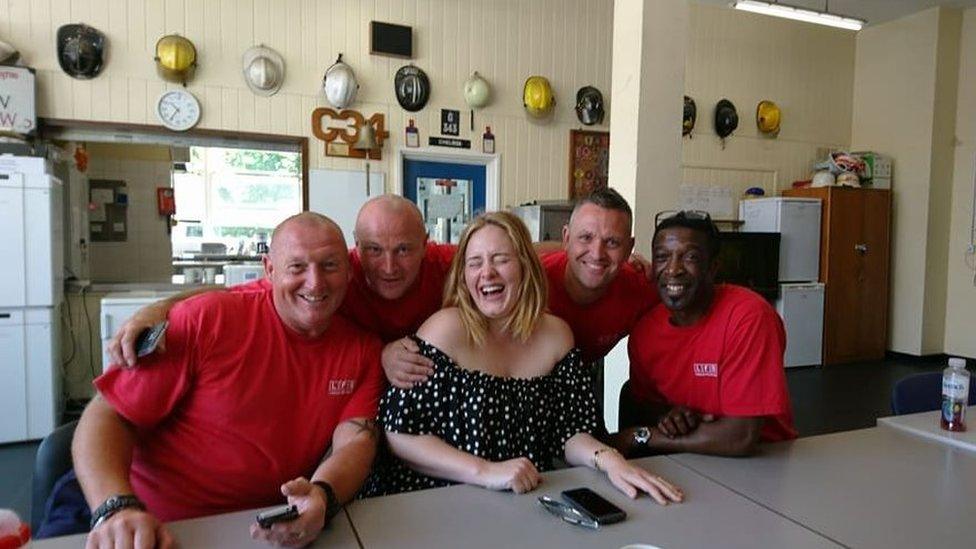 Picture of a laughing Adele with firefighters