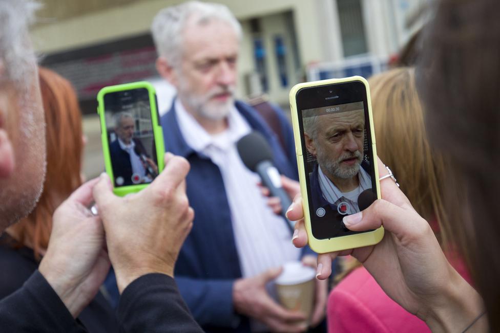 Corbyn speaking while being pictured on mobile phones