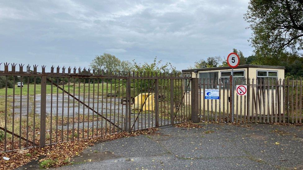 A metal gate and empty brownfield site