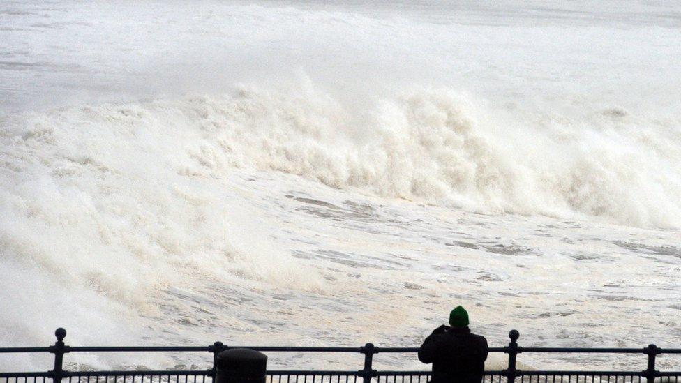 A man watches rough waves come in at Portstewart beach